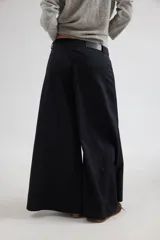 Pantalón de tiro medio con diseño de pierna ancha y cortes curvos que aportan movimiento. Presenta cintura ajustada, bolsillos delanteros y bolsillos plaque en la parte trasera.