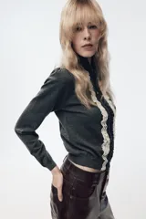 Chaqueta de punto gris oscuro con cuello solapa y manga larga. Presenta un diseño frontal con detalle de puntilla en color crema a contraste y cierre con botones.