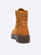 Borcego de gamuza color tostado, con cordones al tono y suela de goma dentada.