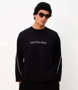 Remera de manga larga Blue Steel, color negro, con diseño de cuello redondo y corte relajado. Presenta un estampado frontal con la palabra 'WORLDWIDE' en letras blancas y detalles de líneas horizontales en contraste.