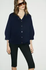 Chaqueta tipo cardigan de lana color azul marino, con cuello en pico, cierre frontal con botones y mangas abullonadas de largo tres cuartos.