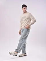 Buzo color beige claro con cuello redondo y puños y cintura acanalados. Estampado frontal con texto en color gris.