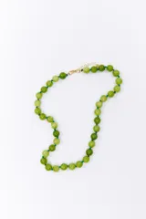 Collar corto de cuentas esféricas de color verde jade, engarzadas con hilo verde y detalles dorados.