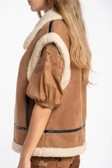 Chaleco estilo gamulán de color negro, con interior y cuello de corderito sintético. Presenta cierre frontal, detalles en cuero sintético y corte oversize.