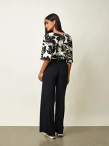 Pantalon tipo palazzo color negro con estampado paisley en tonos beige y blanco, corte holgado y tiro medio.