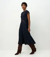 Pollera midi de corte fluido confeccionada en crepé, con pliegues delanteros y cinturón decorativo integrado con hebilla cuadrada. Presenta un diseño minimalista y elegante con cierre discreto.