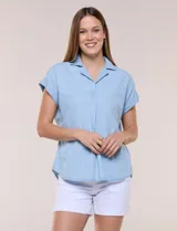 Blusa de diseño recto y textura suave de denim liviano color celeste, con cuello solapa abierto en V, pechera con detalle pespunteado y pliegue central. Presenta mangas cortas caídas con dobladillo fijo y ruedo ligeramente curvo.