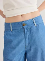 Pantalón jean celeste de corte ancho, con ruedo combinado en un tono más claro.