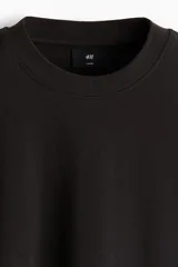 Remera negra de punto de algodón pesado, con cuello redondo ribeteado acanalado, hombros caídos y mangas cortas de corte holgado.
