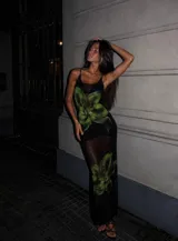 Vestido largo de microtul negro con estampado de flores grandes en tonos verdes. Presenta breteles finos, escote redondo y diseño ajustado al cuerpo con transparencias.