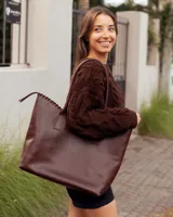 Bolso tipo shopper de cuero color marrón oscuro, con detalle de costura artesanal en el borde superior y correas fijas para llevar al hombro.