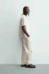 Camiseta de manga corta color crema, con cuello redondo y tejido texturizado con estructura.