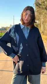 Saco tejido en lana color azul marino con apliques de tela estampada y denim en el frente y puños acanalados con rayas celestes y blancas.