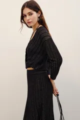 Cardigan cruzado de punto con hilo metalizado, color negro, de manga larga y escote en V profundo.