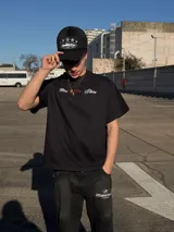 Remera negra de corte oversize con estampado gráfico en la espalda con la inscripción 'New York' en blanco y detalles en rojo, y diseño frontal minimalista.