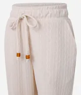 Pantalón zanahoria color crema, con cintura elástica, lazo, bolsillos laterales y superficie texturizada.