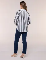 Camisa de crepe blanca con rayas verticales negras, cuello camisero, mangas largas raglán y cierre frontal con botones.