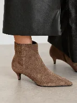 Bota de gamuza color marrón con punta fina y taco fino de 5 cm de altura. Diseño minimalista y sofisticado con cierre lateral.