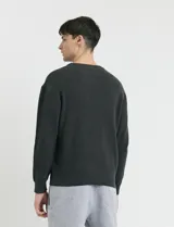 Sweater de punto en color negro, con cuello redondo, mangas largas y puños acanalados.