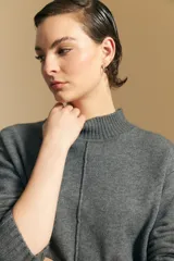 Polera de tejido de punto color blanco, con cuello alto acanalado, hombros caídos y detalle de costura vertical en el frente.