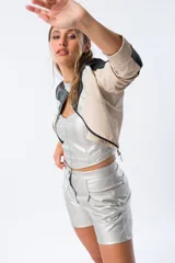 Chaqueta corta plateada de poliéster con terminaciones en beige y negro, cierre frontal y corte ajustado.