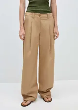 Pantalon wideleg color beige de tiro medio, con cierre de cremallera y botón, trabillas para cinturón y detalle de pinzas frontales.