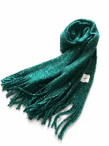 Bufanda tejida de textura suave en color verde esmeralda, con flecos en los extremos y etiqueta decorativa con la inscripción 'HAND MADE'.