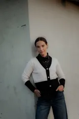 Cardigan bicolor blanco y negro con escote en V, cierre frontal de botones y ribetes negros en cuello, puños y ruedo.