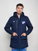 Parka larga de abrigo color azul marino, con capucha, cierre frontal, bolsillos con solapa y bolsillo superior con cierre. Presenta el logo de Umbro y el escudo del Club Nacional de Football.