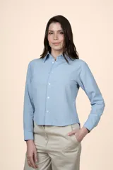 Camisa de algodón color celeste, con cuello camisero, manga larga, cierre frontal con botones y corte a la cintura.
