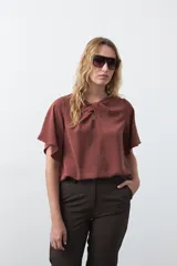 Top negro de manga corta con detalle de nudo en el escote y abertura tipo gota. Presenta una silueta relajada y textura sutil en la tela.