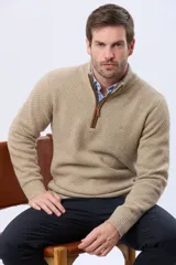 Buzo tejido de punto grueso en color azul marino, con cuello alto y cierre frontal parcial. Presenta detalles en gamuza en la zona del cierre y una textura en relieve en toda la prenda.