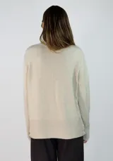 Sweater de punto gris con cuello alto, manga larga con puños acanalados y diseño holgado con costura central vertical.