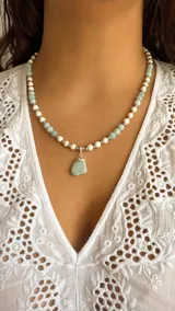 Collar de cuentas de piedras naturales, alternando cuentas blancas veteadas (posiblemente Howlita o Turquesa Howlita) y cuentas de Amazonita verde menta. El collar finaliza con un dije de piedra natural de Amazonita de forma irregular, sujeto con engarce plateado.