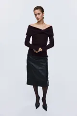 Buzo de punto acanalado con escote off-the-shoulder y detalle de nudo frontal. Presenta un diseño ajustado de manga larga y bajo recto.