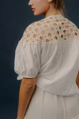 Blusa blanca de algodón con detalles de crochet en la parte superior y mangas cortas abullonadas.