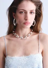 Vestido corto de tejido satinado color celeste, con diseño recto, escote recto y tirantes finos. Presenta detalles de encaje blanco en el escote y en el ruedo.