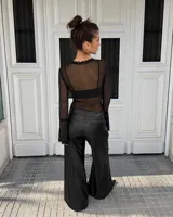 Body de tul transparente color negro, de manga larga con terminación acampanada y detalles de encaje en el escote en V y en los puños.
