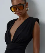 Mono largo de microfibra color negro, con escote en V profundo tipo cruzado, hombreras estructuradas y diseño sin mangas con breteles anchos. Presenta una cintura ajustada y pantalón de corte recto y amplio.