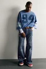 Jeans flare fit de denim azul oscuro con roturas y costuras decorativas en las perneras. Tiro medio y diseño de cinco bolsillos.