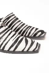 Zueco de cuero con estampado animal print de cebra, diseño de punta cuadrada y detalle metálico lateral. Cuenta con suela de caucho.