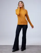 Polera de tejido fino, color rosado, con cuello alto, manga larga y detalle de tajo en los puños.