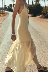 Vestido largo color amarillo pálido, de breteles finos cruzados en la espalda y falda plisada.