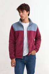 Campera de polar con diseño bicolor, presentando una combinación de color bordó en la parte inferior y gris azulado en la parte superior. Cuenta con cuello alto, cierre frontal completo y bolsillos laterales.