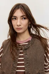 Chaleco de denim marrón con efecto acid wash, cierre frontal con botones metálicos y bolsillos appliquè en el frente.