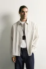 Camisa relaxed fit de algodón con estructura, cuello solapa, manga larga con puño abotonado, bolsillo de parche en el pecho y cierre frontal con botones. Presenta diseño de rayas finas.