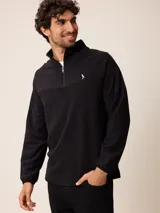 Sweater de polar negro con cuello alto y cierre frontal parcial. Presenta mangas largas con puños elásticos y un pequeño logo bordado en el pecho.