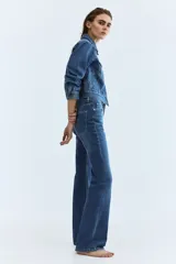 Jean de cinco bolsillos en denim de algodón con stretch. Modelo bootcut de tiro alto, ajustado de cintura a cadera y con corte ligeramente acampanado desde la rodilla hacia el bajo. Presenta raya marcada en la parte delantera y trasera.