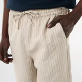 Pantalón de lino color beige con sutiles rayas verticales oscuras, de corte recto y holgado, con cintura elastizada y cordón ajustable.