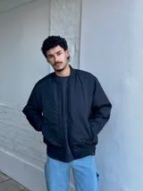 Campera bomber negra de nylon con cierre frontal y bolsillos laterales.